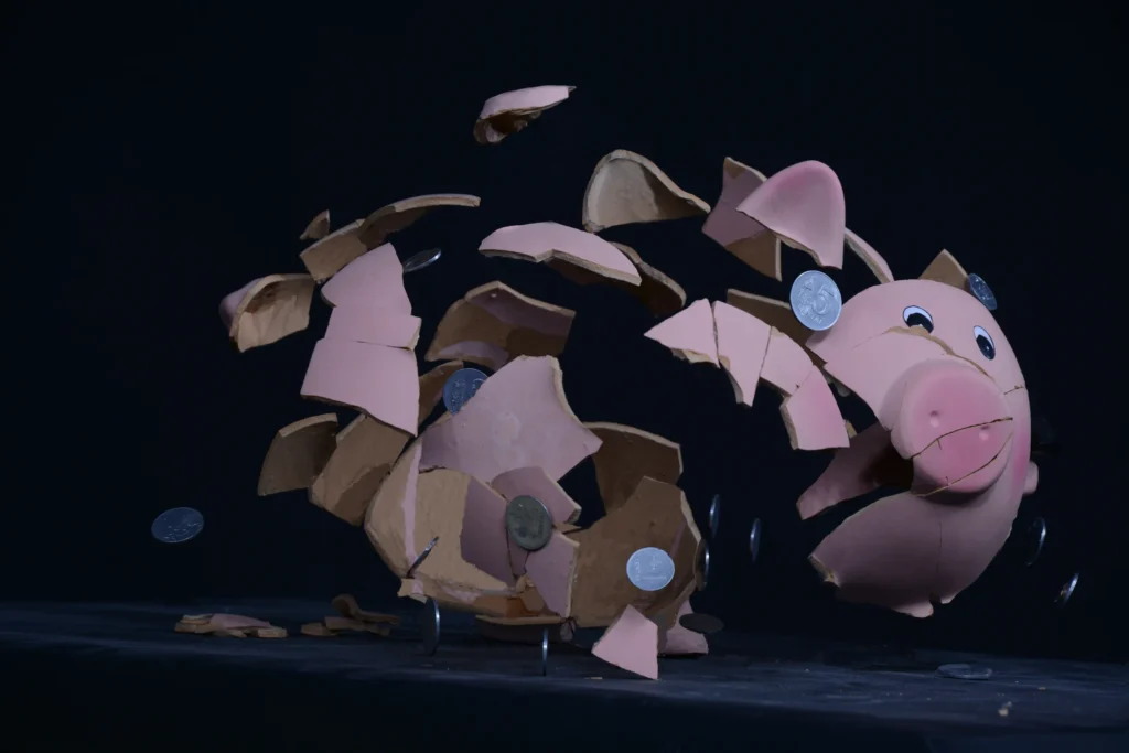 A broken pieces of piggy bag and coins scattered in air.
